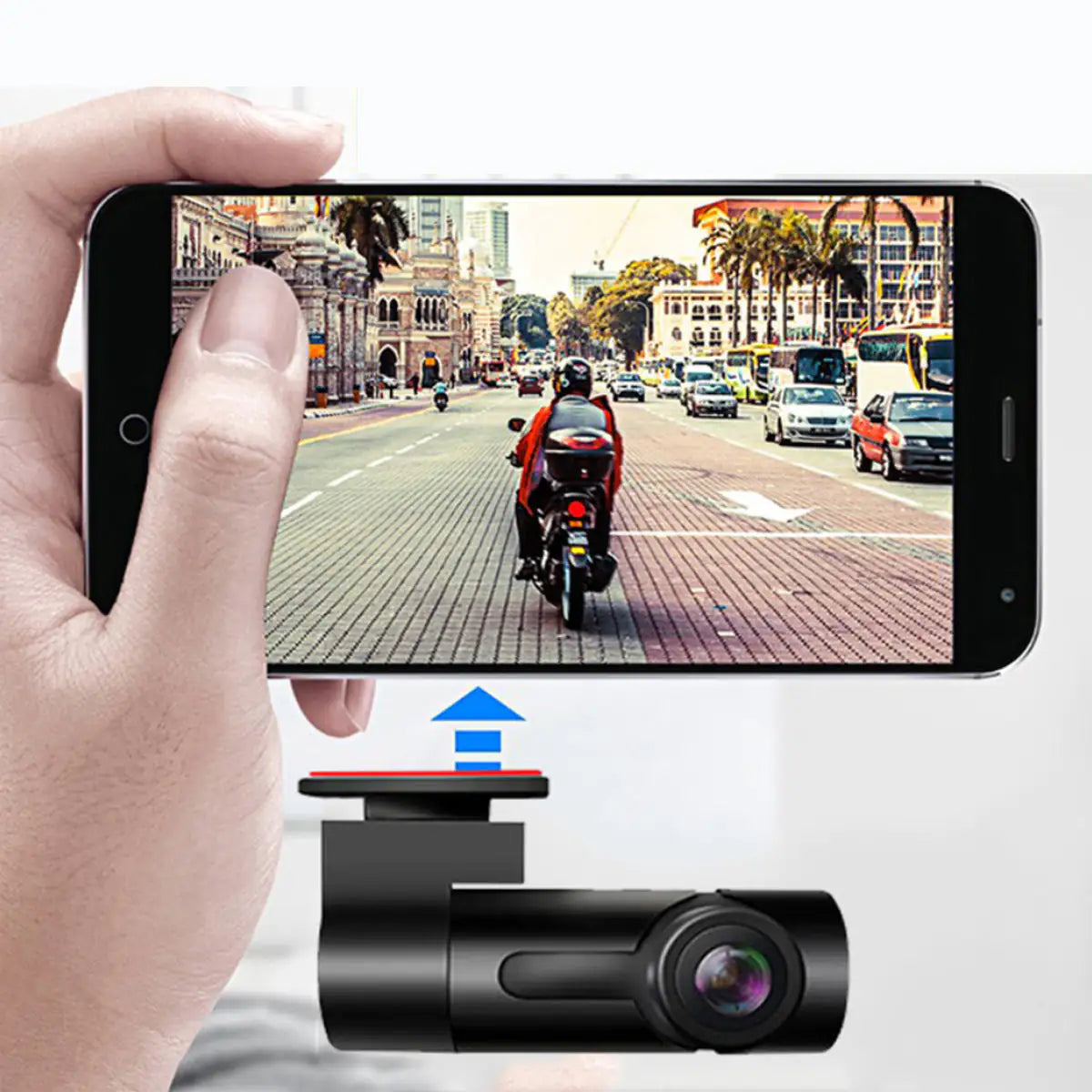 Hand holding a smartphone displaying a video of a motorcycle on a city street, with a dash cam in the foreground.