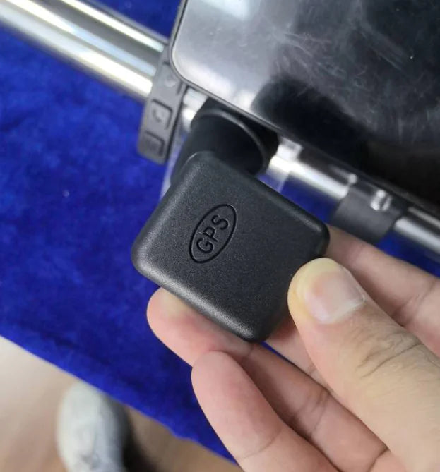 Black device with 'GGS' logo held by a hand against a blue background